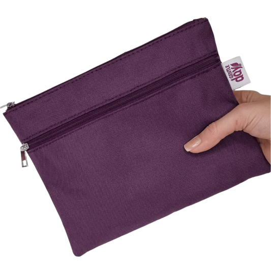 Purple zippered pouch held by a hand with a visible brand tag on a white background