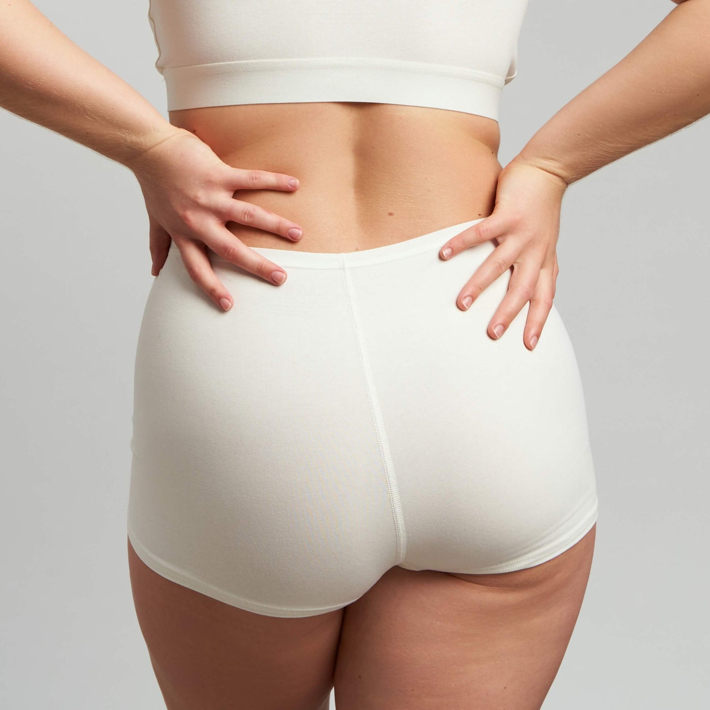 A rear view of a person wearing a white high-rise boyshort panty