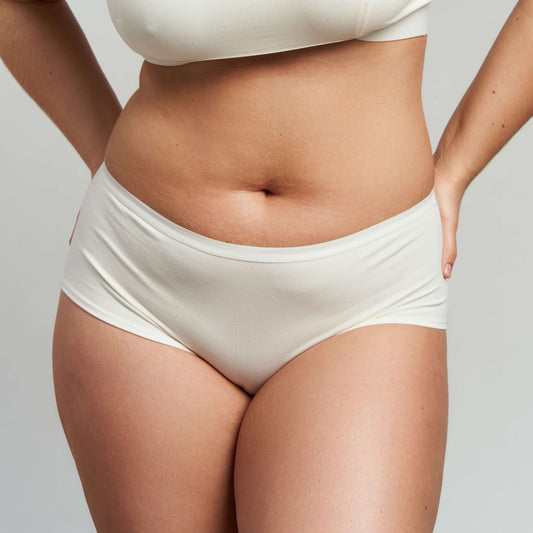 Front view of a person wearing ecru-colored low-rise hiphugger panties