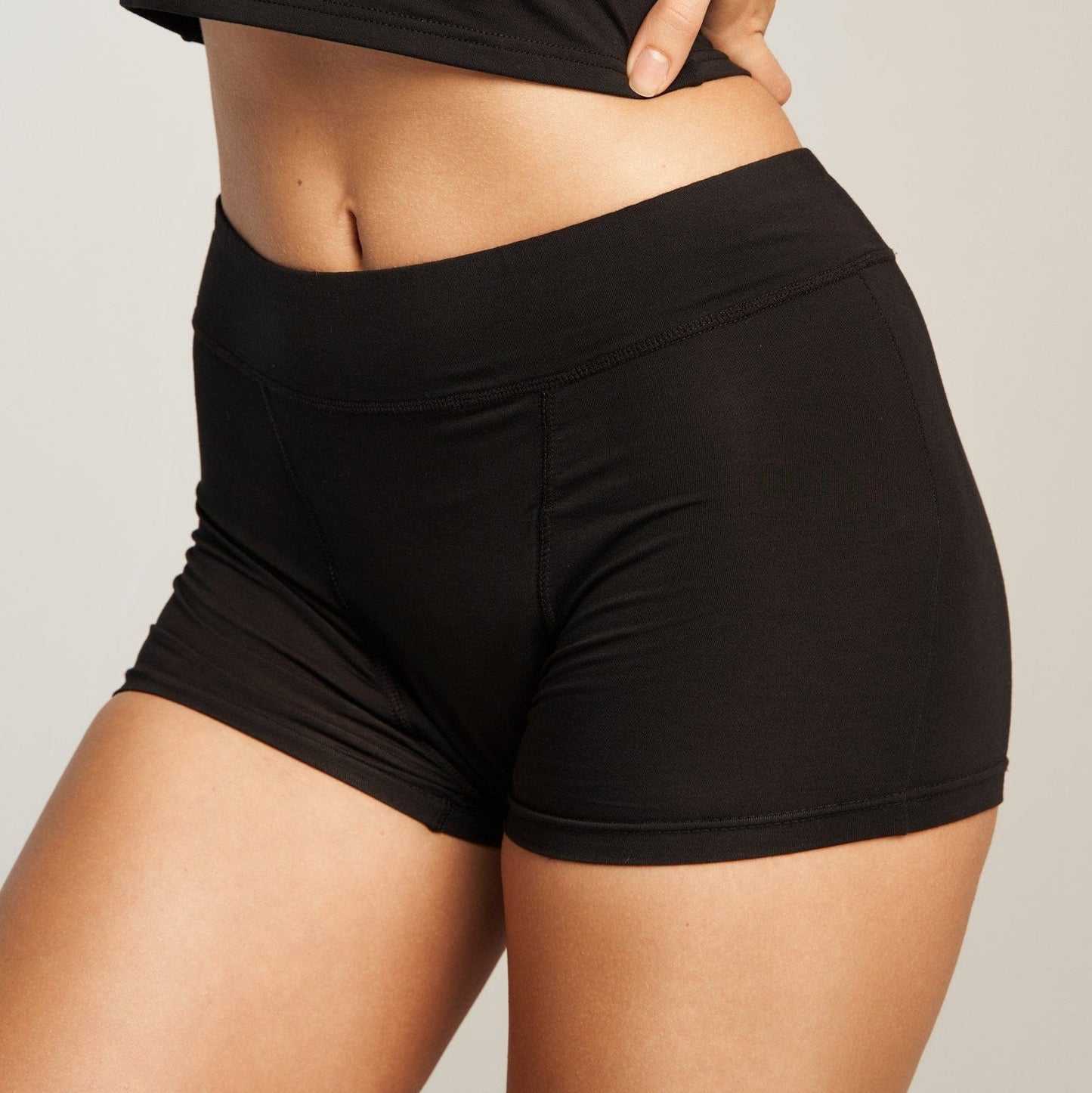 Person wearing black athletic shorts and top on a plain background